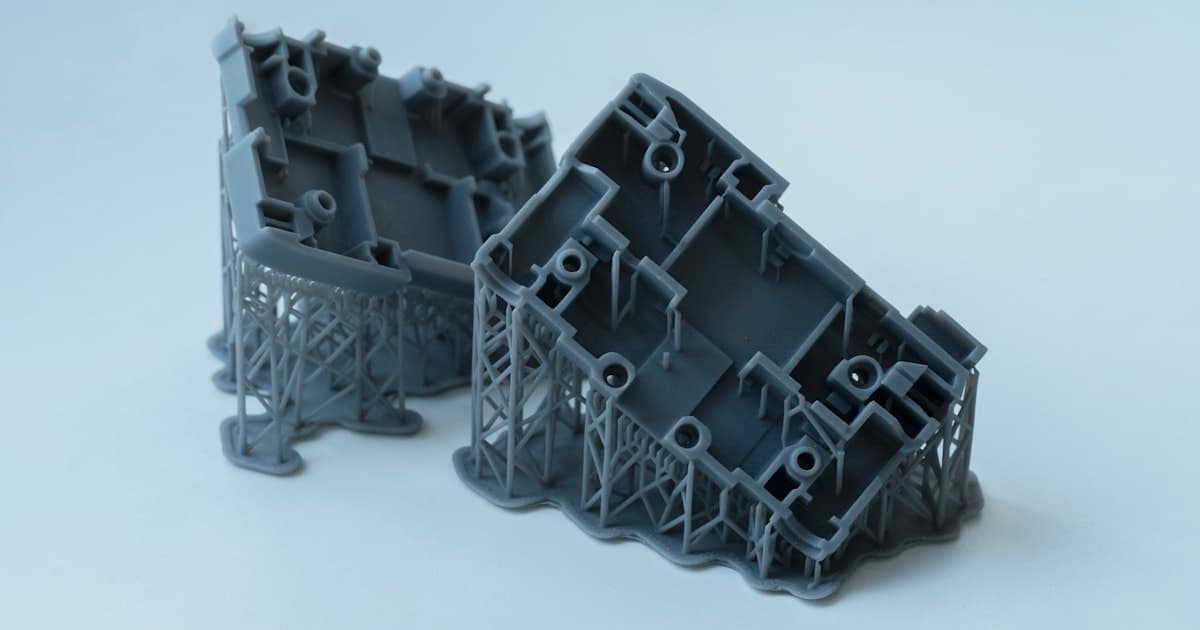 SLA 3D printer with orange resin building a complex engineering part under UV light in a laboratory