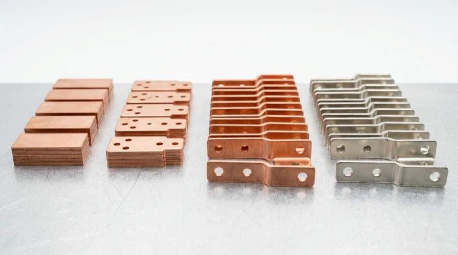 Copper sheet metal parts showing laser-cut edges, formed bends, and drilled holes from blanking, piercing, and forming