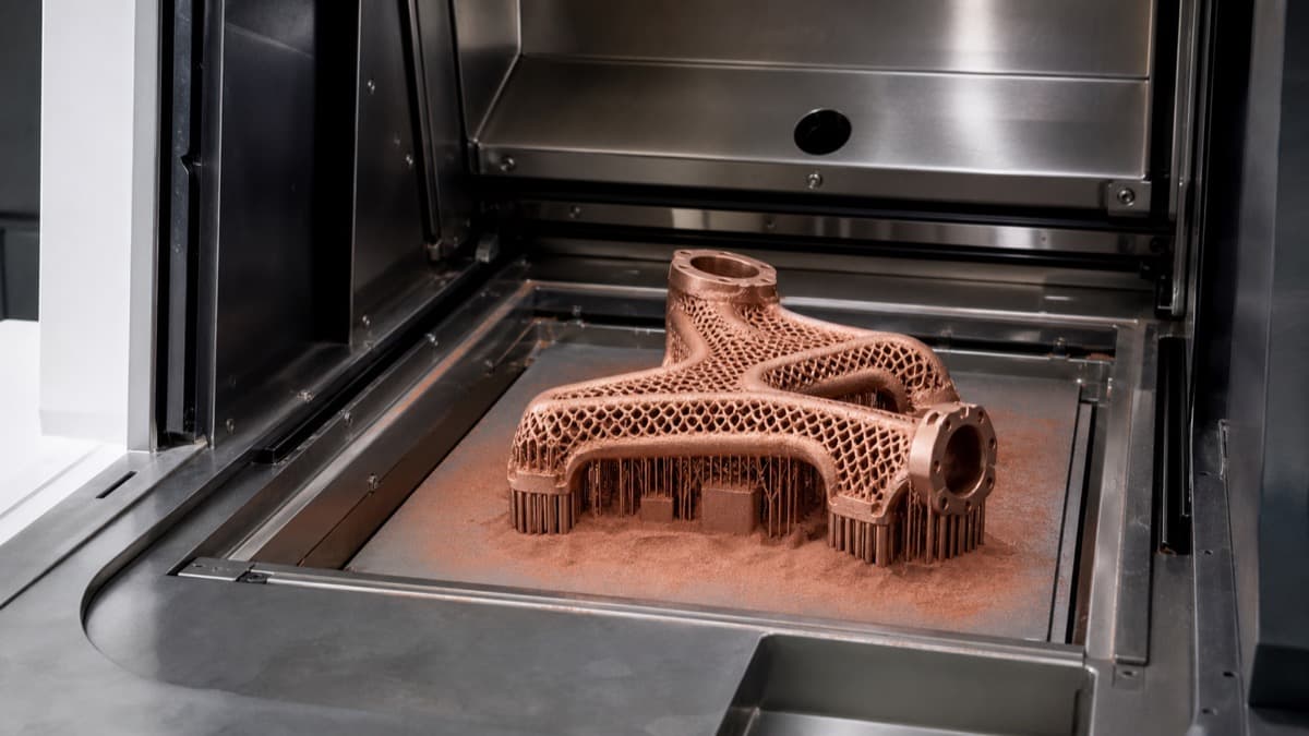 Copper-colored lattice component being built on a metal powder-bed fusion build plate